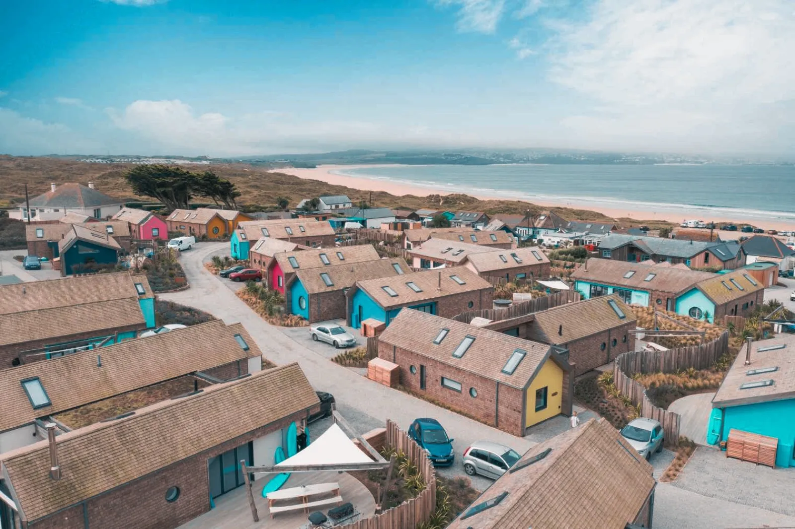 Aerial view of the beach houses at Three Mile Beach, Cornwall, with the bay beyond